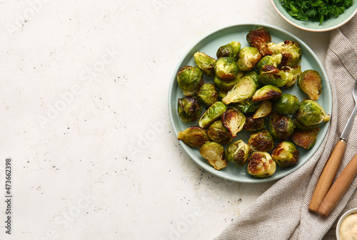 Plate with delicious roasted Brussels cabbage and greens on light background