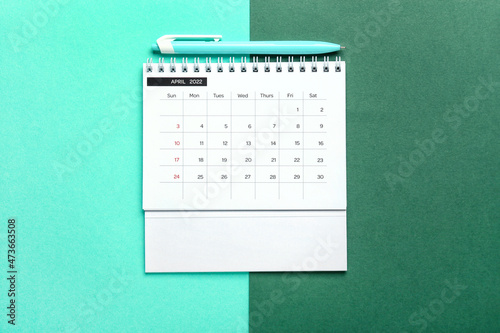 Classic flip paper calendar for April 2022 and pen on color background