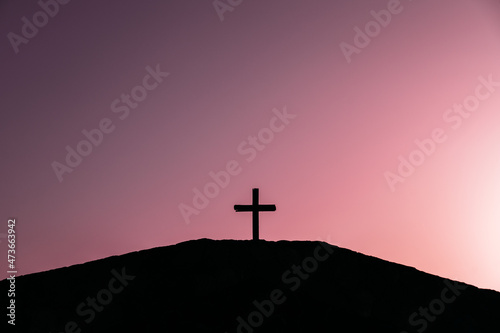 Cross on hill against sunset sky photo