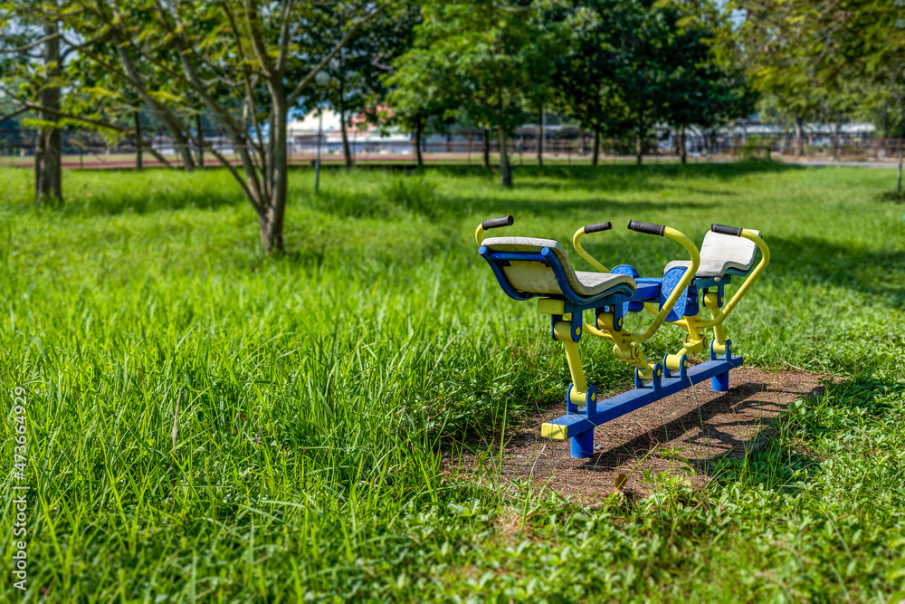 Abandoned old exercise machines in the park covered with plants and weeds. The impact of the covid-19 epidemic.