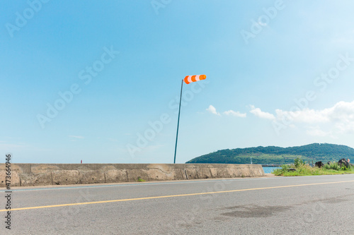 Orange wind direction flag next to the road. photo