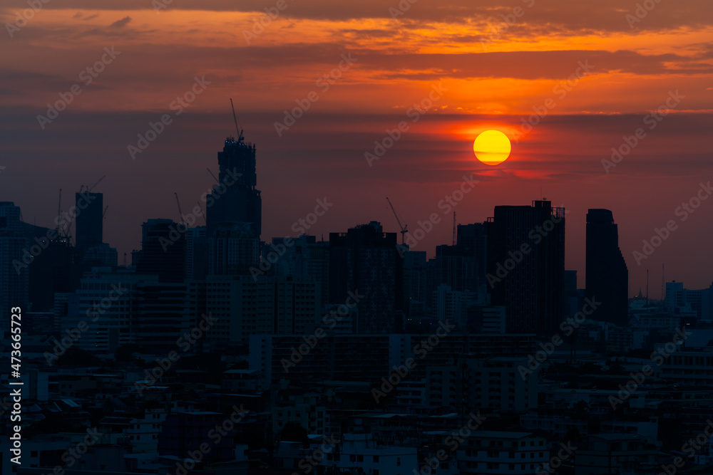 The sun was setting in the evening, a golden orange light shone all around. with a backdrop of tall buildings in a large city in the shadows