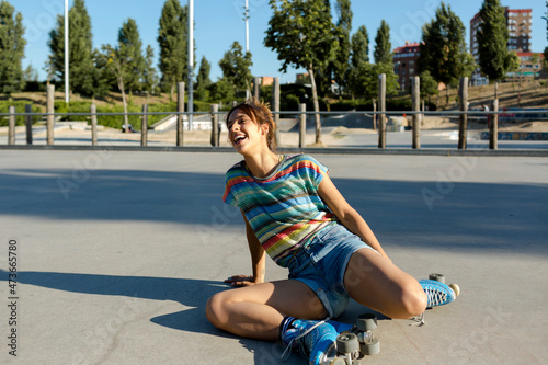 Roller-skater girl on ground laughing after falling photo