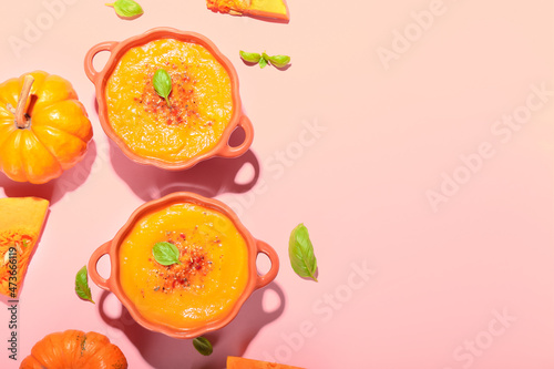 Fototapeta Naklejka Na Ścianę i Meble -  Pots with tasty pumpkin cream soup on pink background
