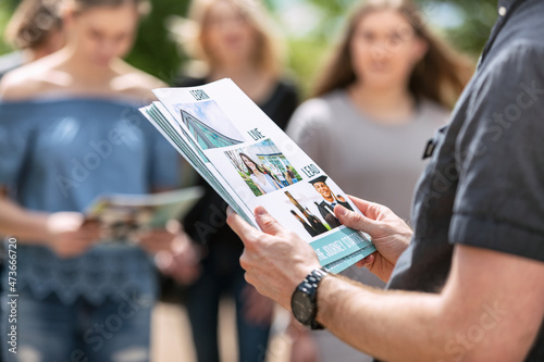 Tour: Guide Holds Stack Of Information Folders To Hand Out photo