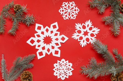 Fir branches and beautiful paper snowflakes on red background