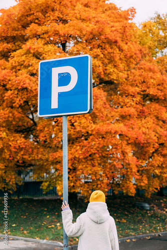 The girl is standing at the parking sign. photo