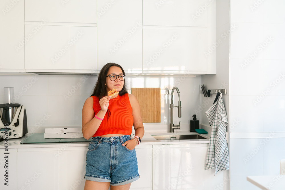 Joyful woman eating fast food in kitchen Joyful woman eating fast food in kitchen