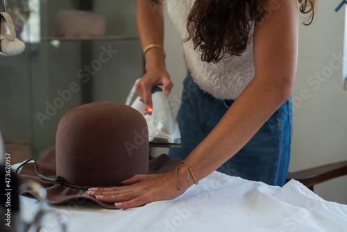 Anonymous woman using an iron to shape a fedora hat photo