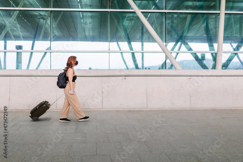 Woman pulling luggage at airport outdoors