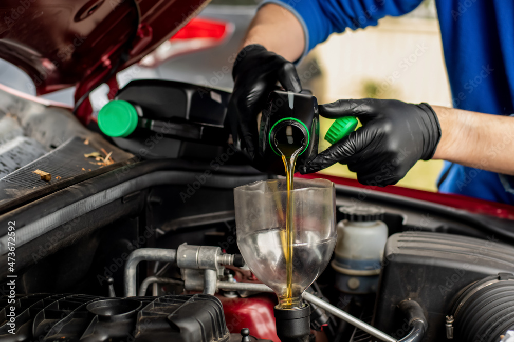 Obraz premium Changing replacement car oil with plastic bottle. DIY change engine motor oil. At home vehicle maintenance. Garage mechanic