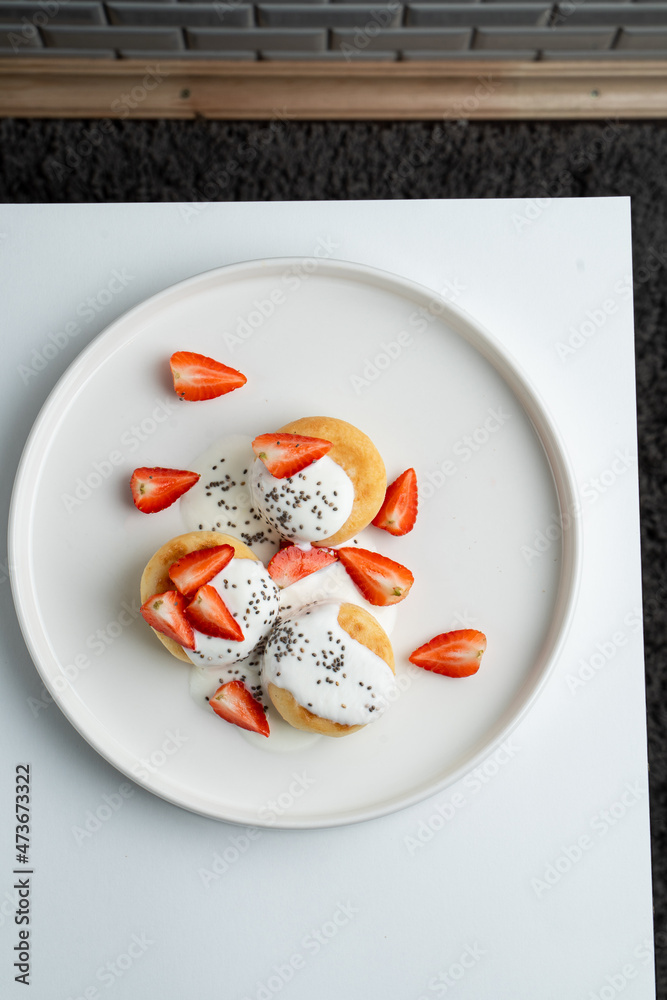 Golden roasted syrniki with strawberry and sour cream, appetizing photo of sweet russian breakfast Golden roasted syrniki with strawberry and sour cream, appetizing photo of sweet russian breakfast