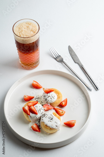Top view of ukrainian cottage cheese fritters on white table with a cup of coffee