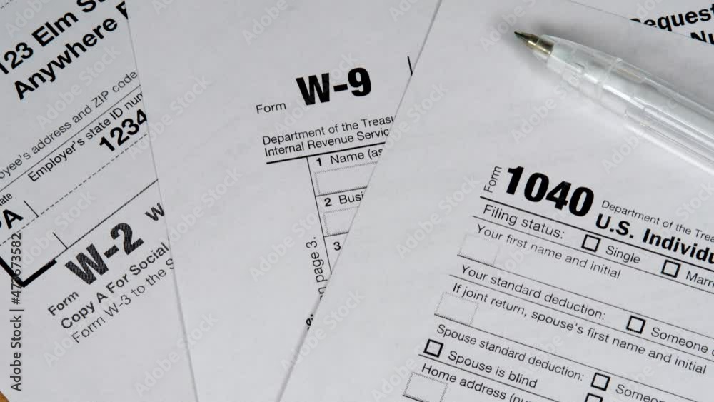 Different taxes forms for taxes payments with pen. Income tax return deduction refund. Savings, finances and economy concept. Form 1040 U.S. income tax return. W-2 and W-9 document