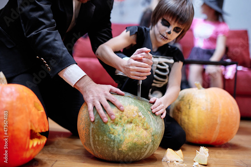 Father and son carving Halloween pumpkin photo