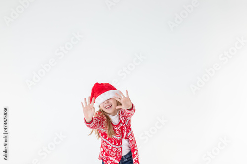portrait of happy girl dancing ,wearing red christmas sweater and santa hat isolated on white background.young caucasian joyful smiling blonde girl in a Christmas red deer sweater is happy.