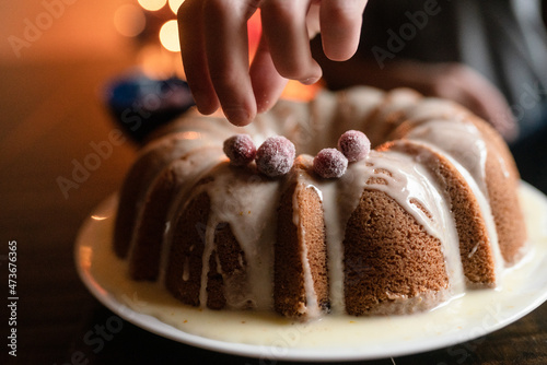 Hand decorates bundt cake with sugared cranberries photo