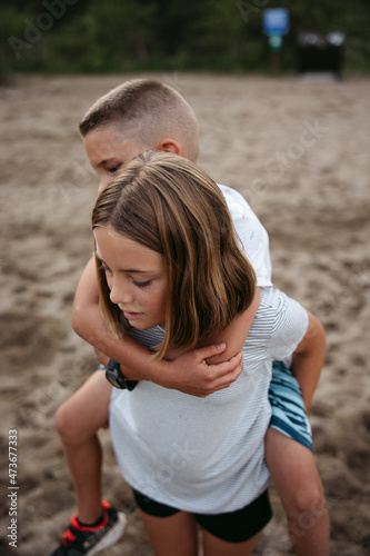 Girl giving younger boy a shoulder ride.