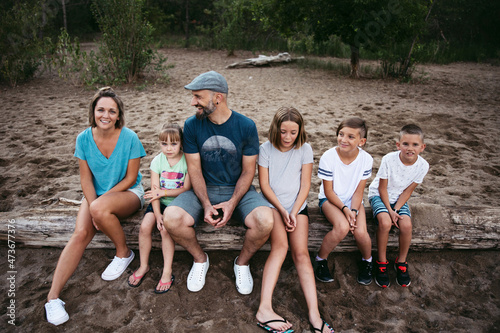 Large family sitting together on log.