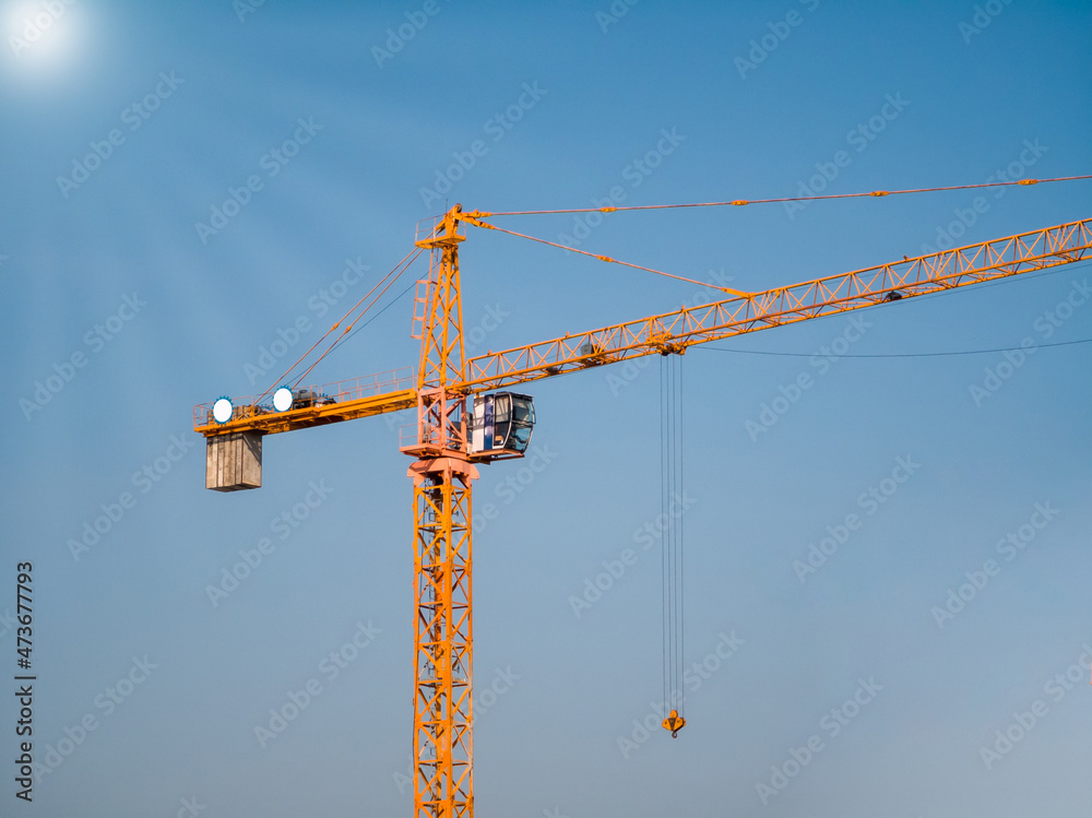 Orange Hammerhead Tower Crane. The background is the sky, and lens flare white (sun shines). Orange Hammerhead Tower Crane. The background is the sky, and lens flare white (sun shines).