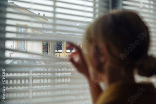 Female peeking through shutters