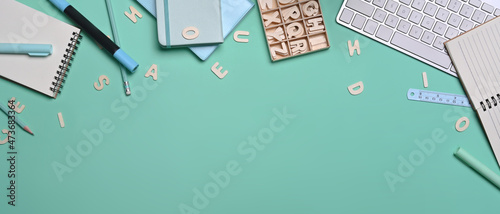 Top view various stationery and keyboard on green background.