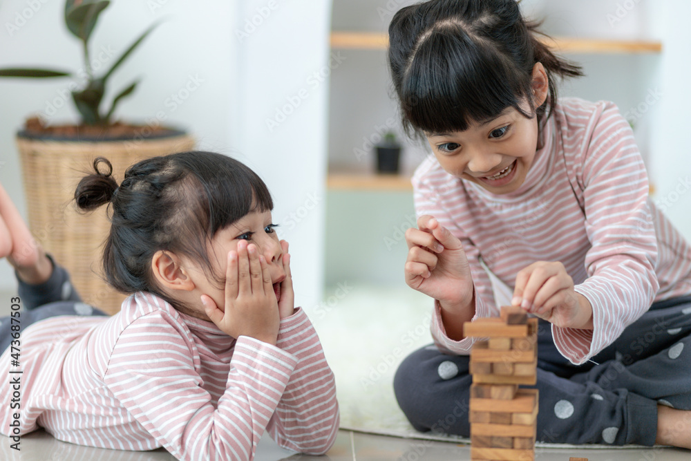 Asian sibling girl playing wooden stacks at home Asian sibling girl playing wooden stacks at home