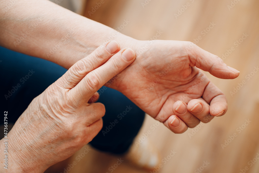 Female old hand measure taking pulse check arm pulse. Elderly woman heart health.