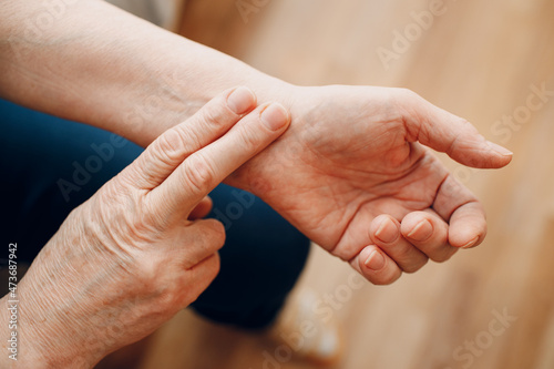 Female old hand measure taking pulse check arm pulse. Elderly woman heart health. © primipil