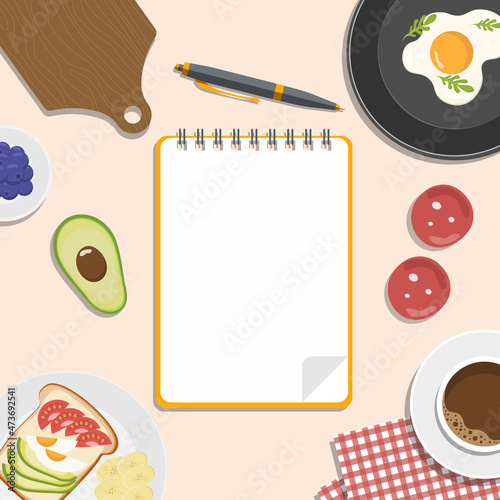 Recipes book. Notepad and pencil for writing recipes surrounded by vegetables, coffee, eggs and a cutting board.