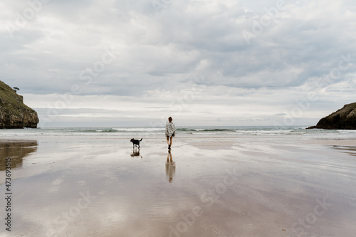 Woman and dog  exploring  wild empty beach photo