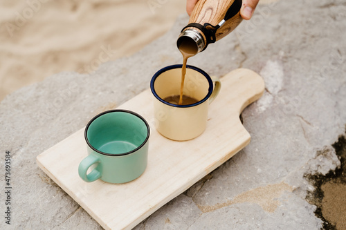 Pouring coffe into mug outdoors photo