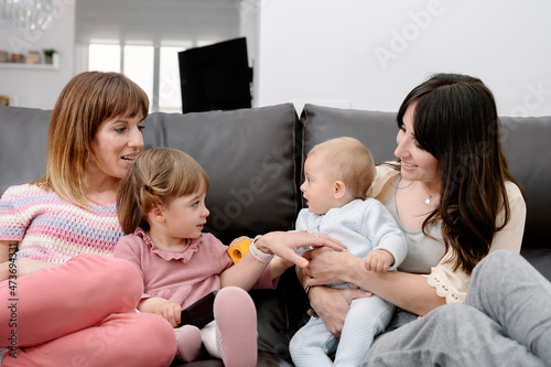Moms sitting and playing with their children on couch