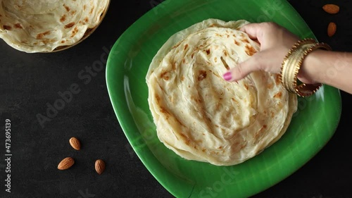 Indian flat bread Kerala porotta woman hand serving eating Malabar porotta paratha layered bread 4K video footage whole wheat flour Maida India  chapati fulka parantha rumali roti side dish meat curry photo