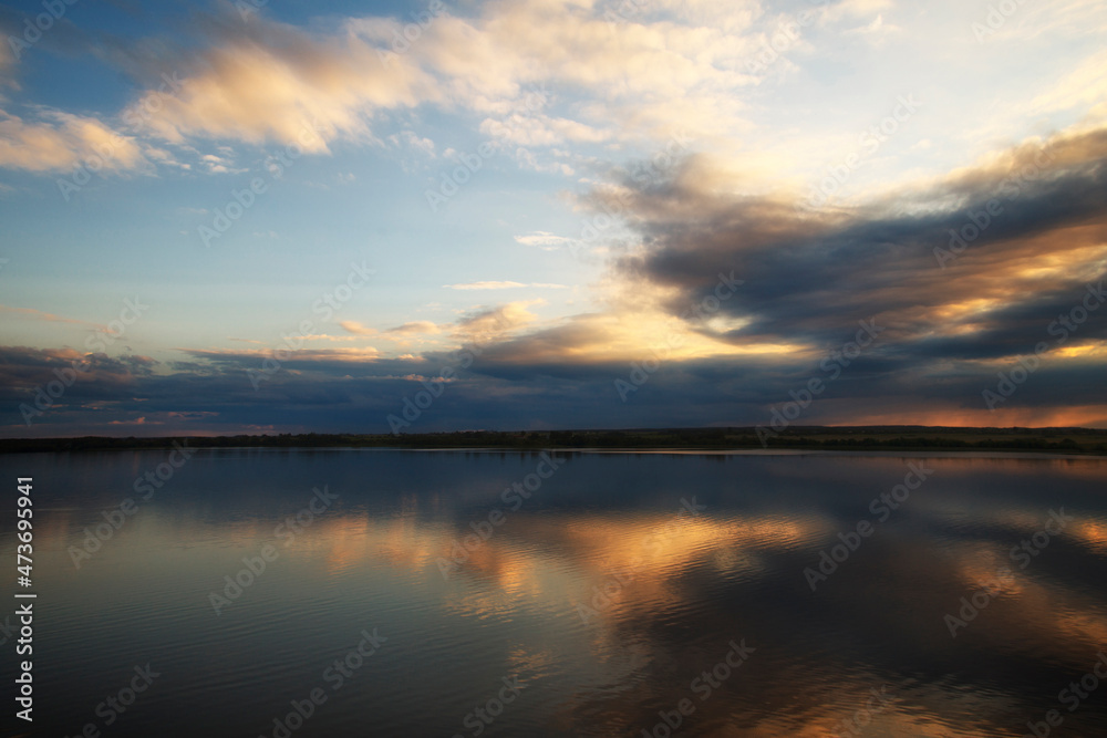 Photo of a sunset in the beautiful blue sky with clouds that reflects on the water of the river. Nature concept
