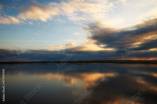 Photo of a sunset in the beautiful blue sky with clouds that reflects on the water of the river. Nature concept