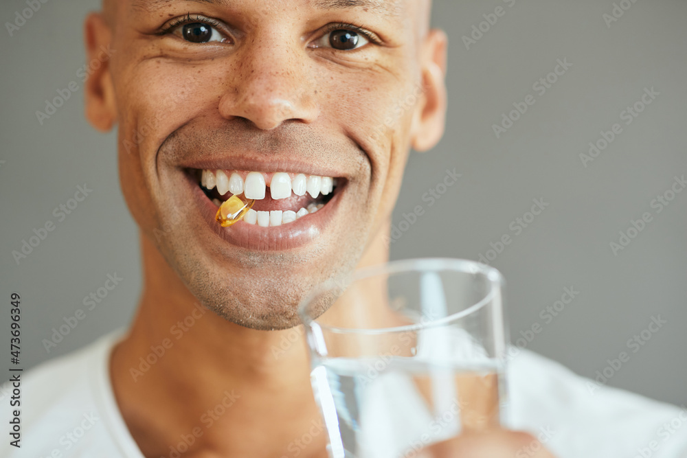 Close-up of happy black man takes omega-3 pill and looks at camera.