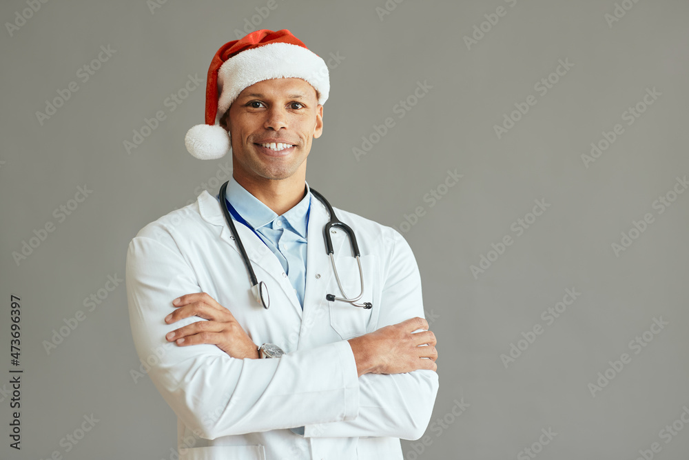 Confident African American general practitioner wears Santa hat and looks at camera. Confident African American general practitioner wears Santa hat and looks at camera.