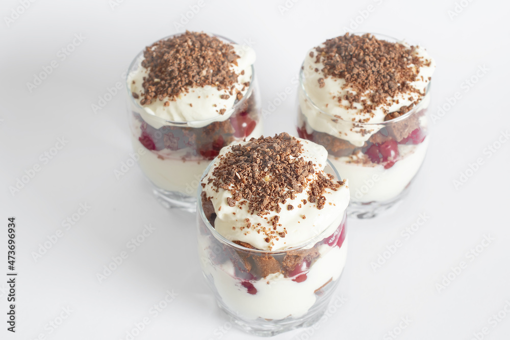 Biscuit cake with cream and cherries in a glass on a white background Biscuit cake with cream and cherries in a glass on a white background