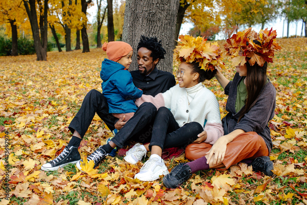 Diverse family trying on wreath of yellow leaves Diverse family trying on wreath of yellow leaves