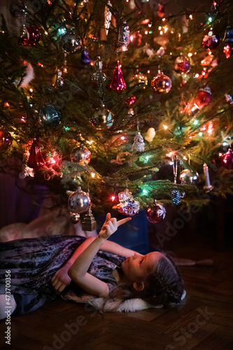 Little girl laying under a Christmas tree photo