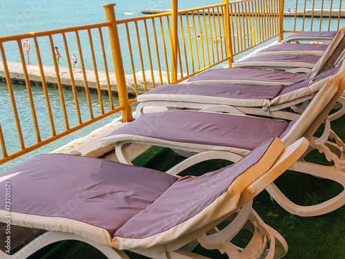 Empty deck chairs with mattresses on the air aerarium for relaxing on the beach of a hotel or resort, against the background of the sea photo