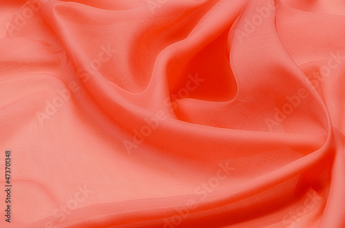 Close-up texture of natural red or pink fabric or cloth in same color. Fabric texture of natural cotton, silk or wool, or linen textile material. Red canvas background.