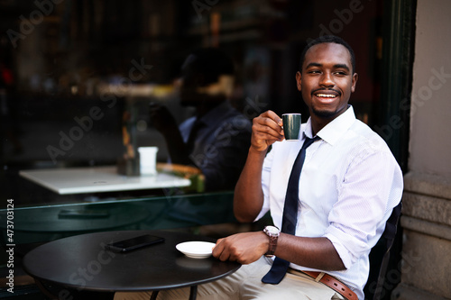 African businessman drinking coffee in cafe. Happy smiling man enjoy in fresh coffee..