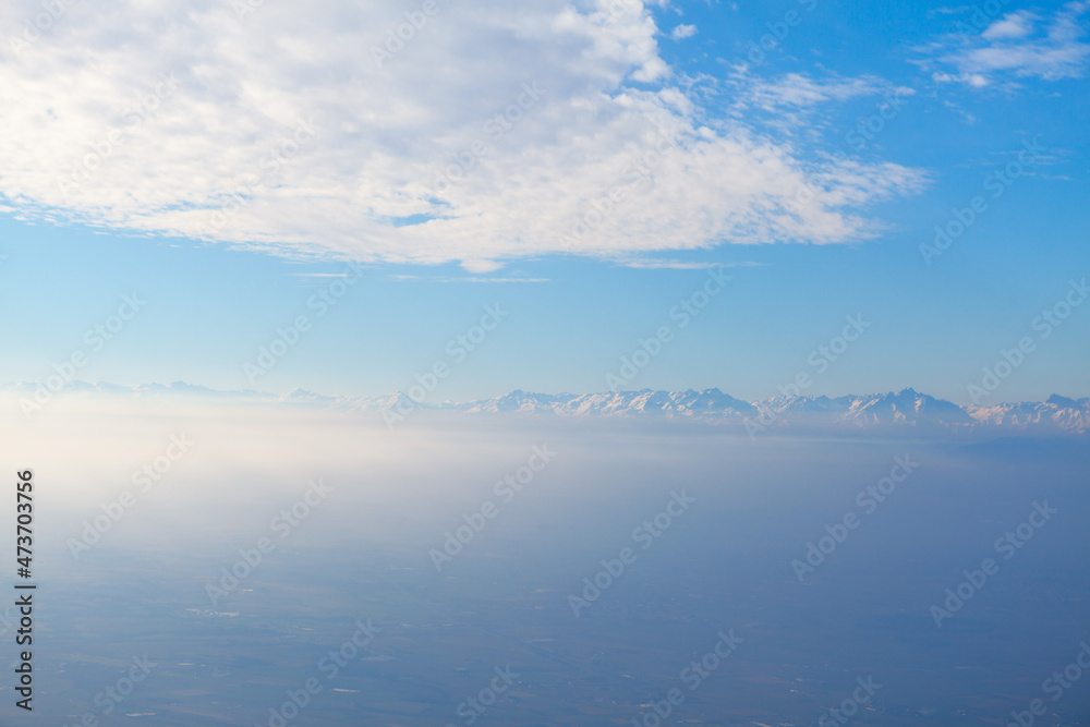 Clouds over the mountains in the haze . Snowy mountains at horizon 