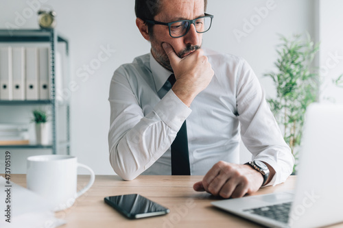 Foto Contemplative caucasian businessman looking at laptop computer screen in busines
