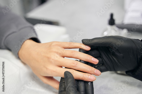 Unrecognized female client receiving nails treatment in salon
