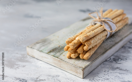 Italian grissini or salted breadsticks on a light stone background. Fresh italian snack with sesame seeds. photo