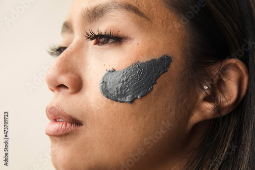 Model wearing grey clay mask on her face