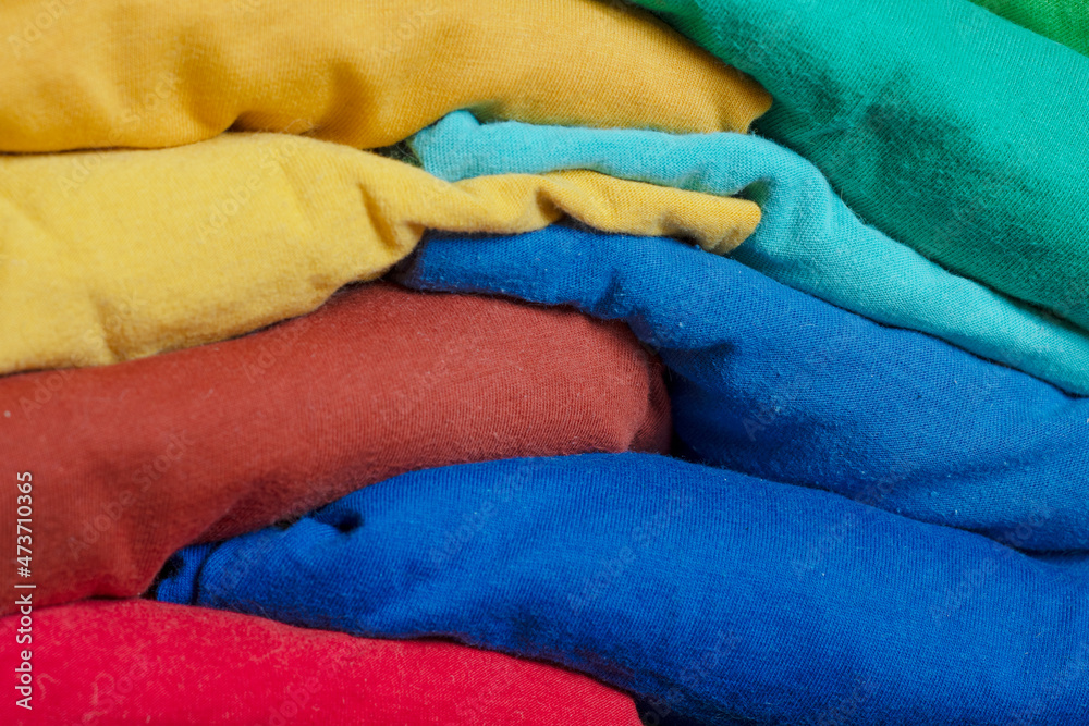 A stack of multicolored fabric without inscriptions. Background with folded clothes. T-shirts of different colors